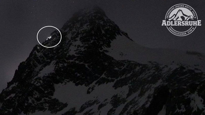 Snow-covered Austrian mountain at night with climber lights visible near the peak, related to boyfriend who abandoned woman.