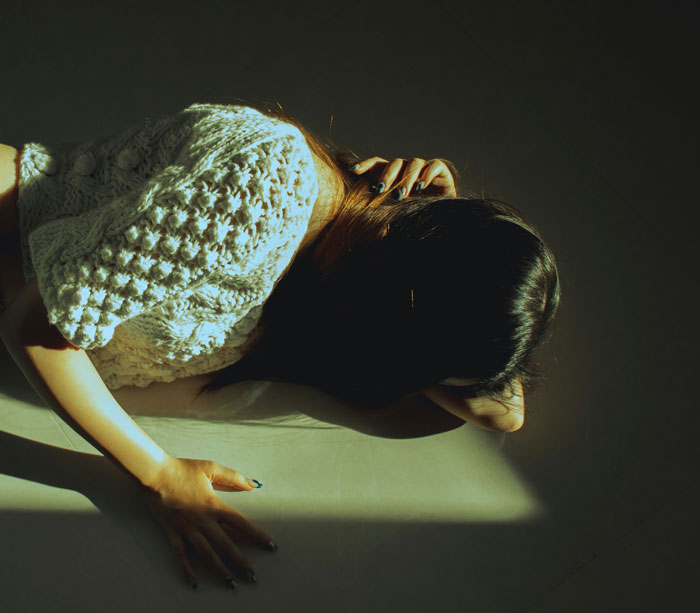 Person lying on the floor under direct light, symbolizing embarrassment in front of doctors during awkward moments.