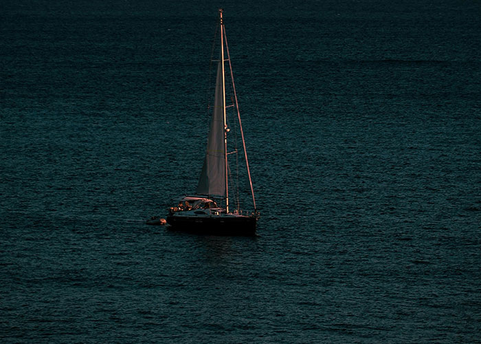 Sailboat alone on dark water, evoking a creepy and mysterious scene in a remote and isolated place.