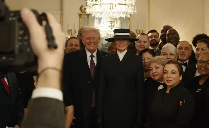 Photographer capturing Melania Trump and Donald Trump posing with a group of people in an elegant room. Photographer capturing Melania Trump and Donald Trump posing with a group of people in an elegant room.