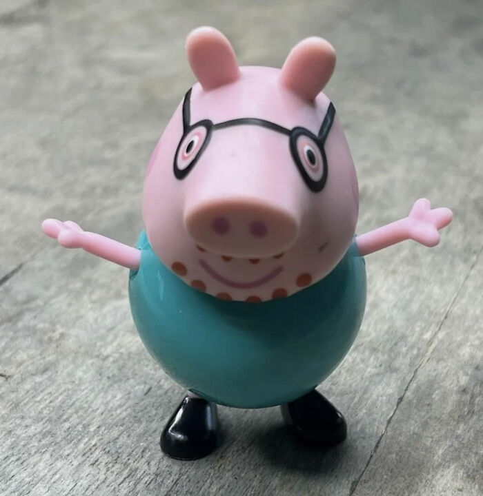 Toy pig character with glasses standing on wooden surface, perfect for kids' spicy roasts and funny moments.