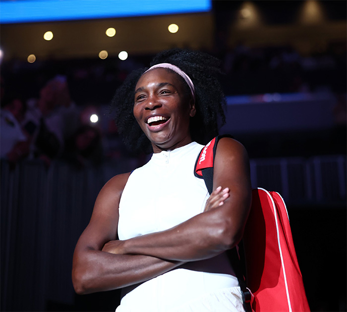 Venus Williams with a red bag in a bright arena, highlighting celebrities with rare conditions awareness.