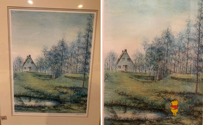 Thrifted painting of a house and trees personalized with a funny, unexpected addition of a small cartoon character by a pond.