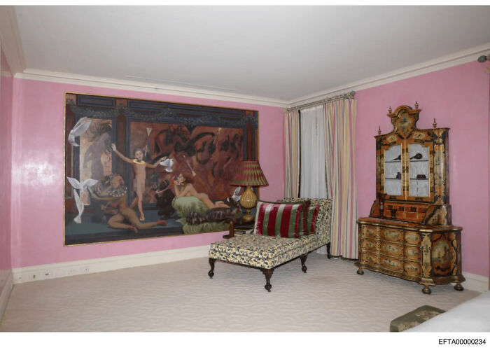 Room in NYC townhouse featuring troubling art on pink walls and vintage furniture including a chaise lounge and ornate cabinet.
