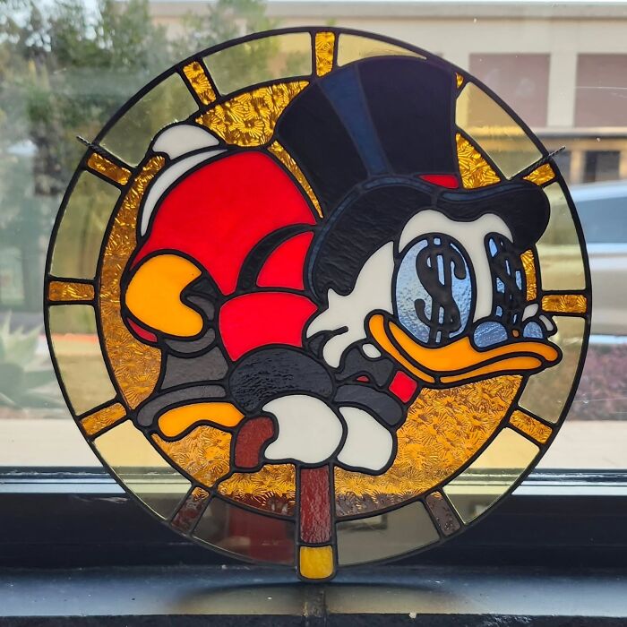 Stained glass sign featuring a vivid pop culture icon of a duck wearing a top hat with dollar sign eyes.