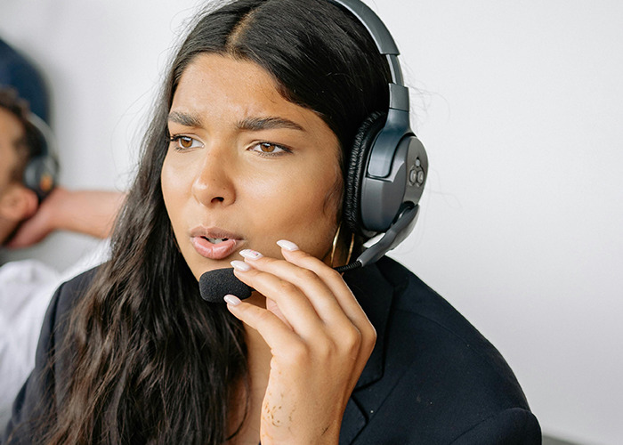 Young 911 operator with headset, focused on answering dumb non-emergency calls in a busy communication center.