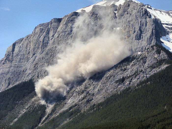 Rockslide on a mountain slope showing natural disaster with people instinctively sensing danger and needing to leave quickly.