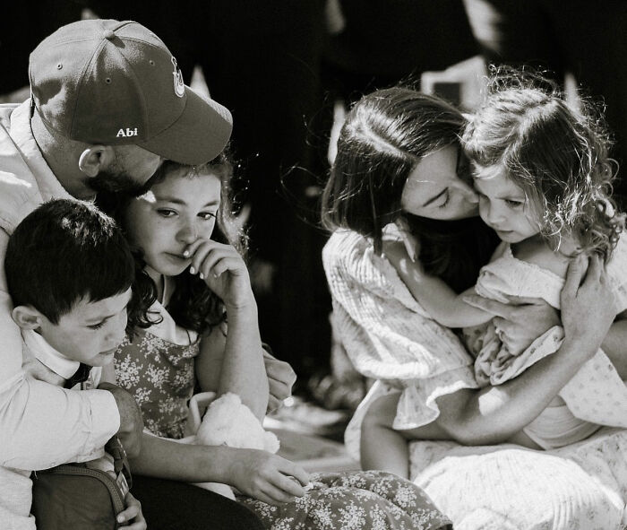 Family grieving together, mother comforting young daughter, reflecting the influencer's daughter's passing and family loss.