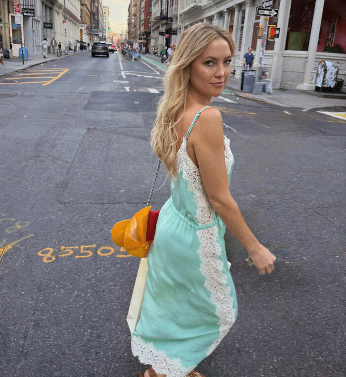 Kate Hudson wearing a mint green dress with white lace detail, walking on a city street with a casual pose. Kate Hudson wearing a mint green dress with white lace detail, walking on a city street with a casual pose.