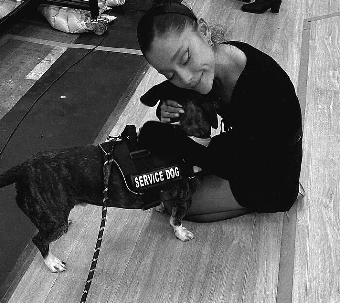 Ariana Grande sitting on the floor hugging a service dog, highlighting struggles and family support for mental health.