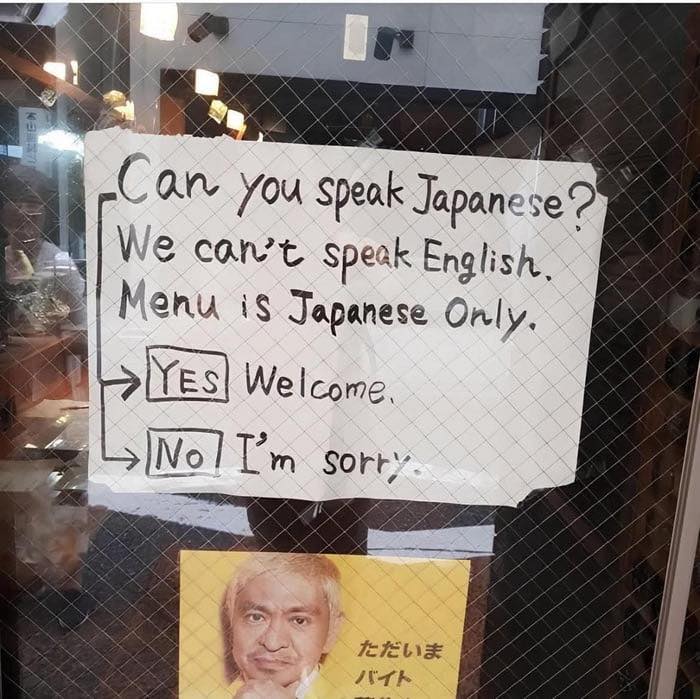 Handwritten sign humorously explaining language barrier with Japanese menu, showcasing sarcasm and funny posts about shared brain cell.