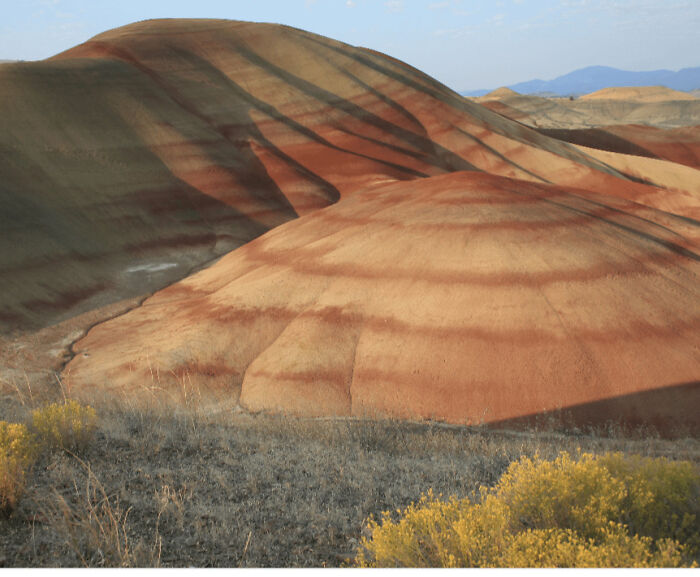 Layered hills with vivid red and brown stripes in a natural landscape, one of the places that look AI generated but are real.