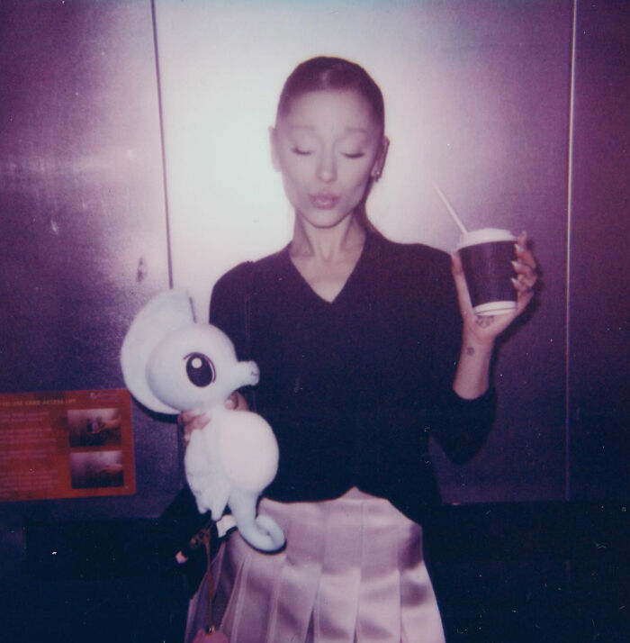 Ariana Grande holding a stuffed animal and a cup, highlighting family member revealing singer struggles and not in a healthy place.