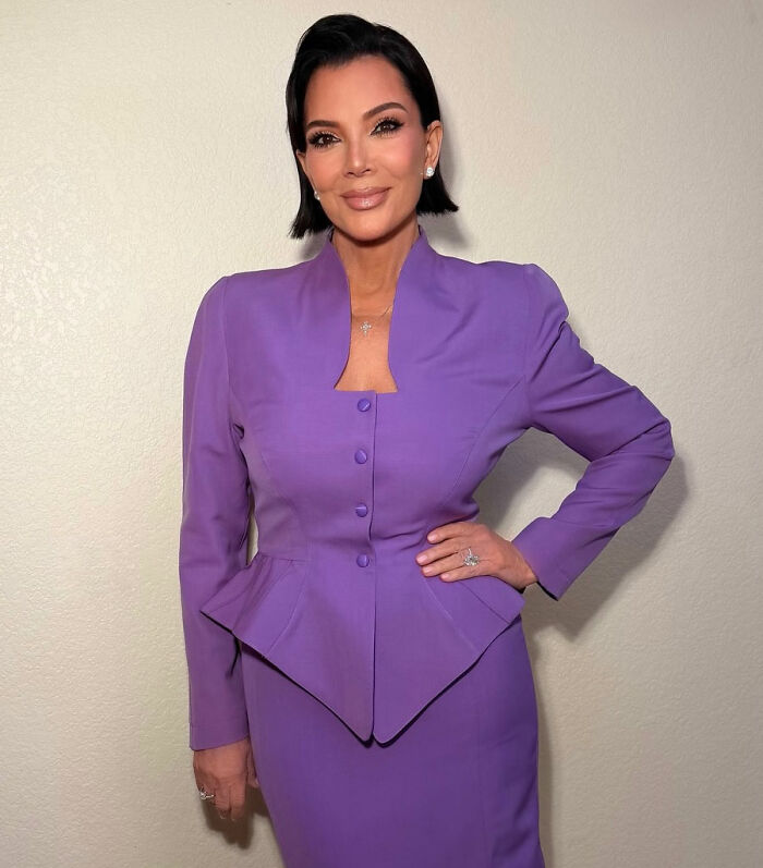 Kris Jenner standing confidently in a purple outfit showing her hands after viral $100k facelift reveal.