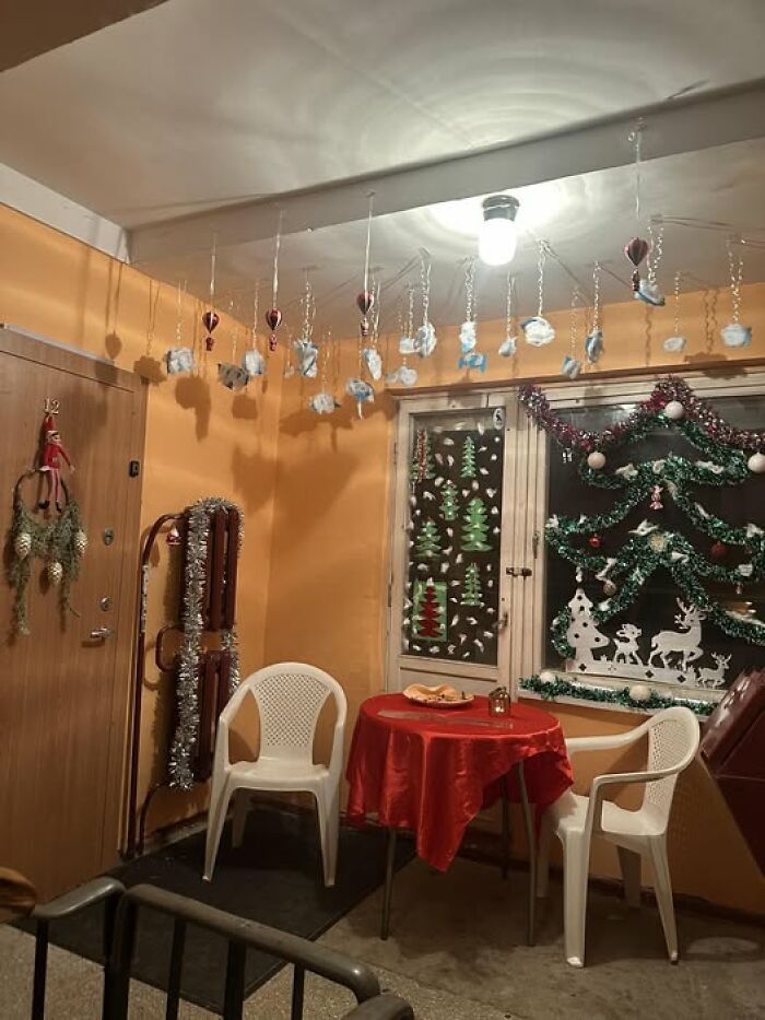 Lithuanian apartment building Christmas decorations with tinsel, paper cutouts, and hanging ornaments in a small hallway.