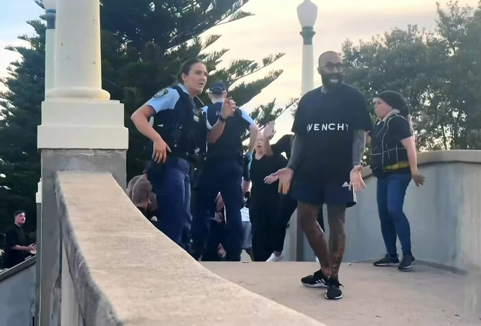 Police officers interacting with a man and crowd at Bondi Beach during an incident that sparked widespread outrage.
