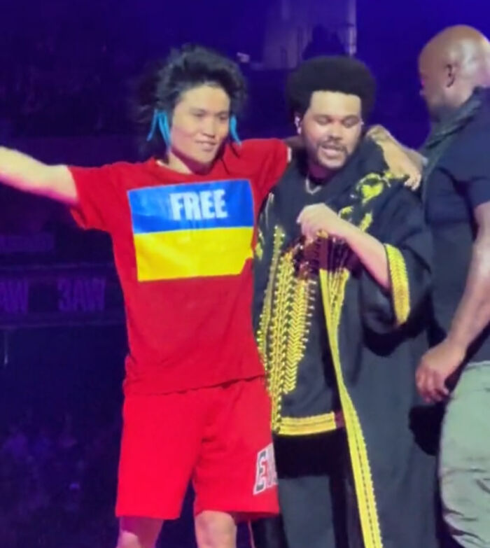 Man in red shirt escorted by security at Lady Gaga concert amid trouble involving Ariana Grande attack case.