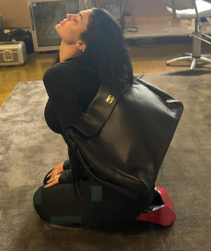 Woman in black outfit with large black leather backpack, highlighting Timoth&eacute;e Chalamet red carpet look odd detail.