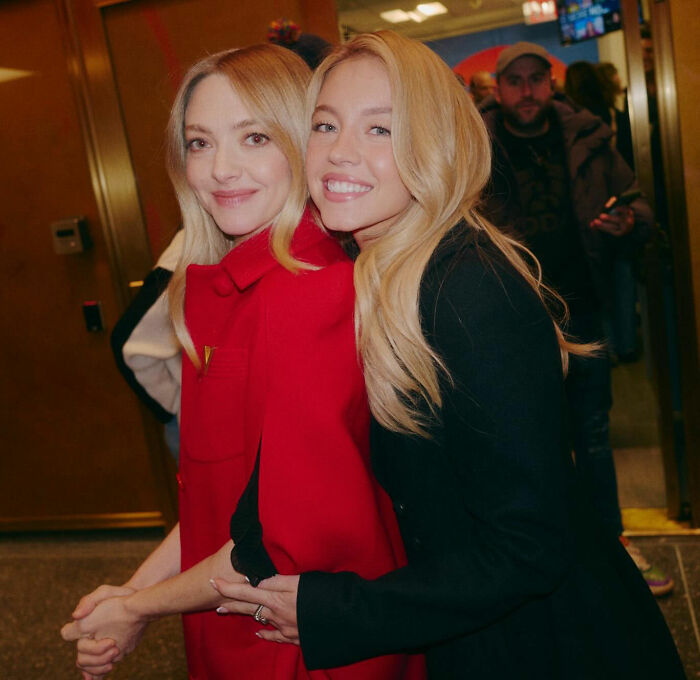 Two smiling women with blonde hair embrace indoors, relating to Sydney Sweeney and lie detector test controversy.