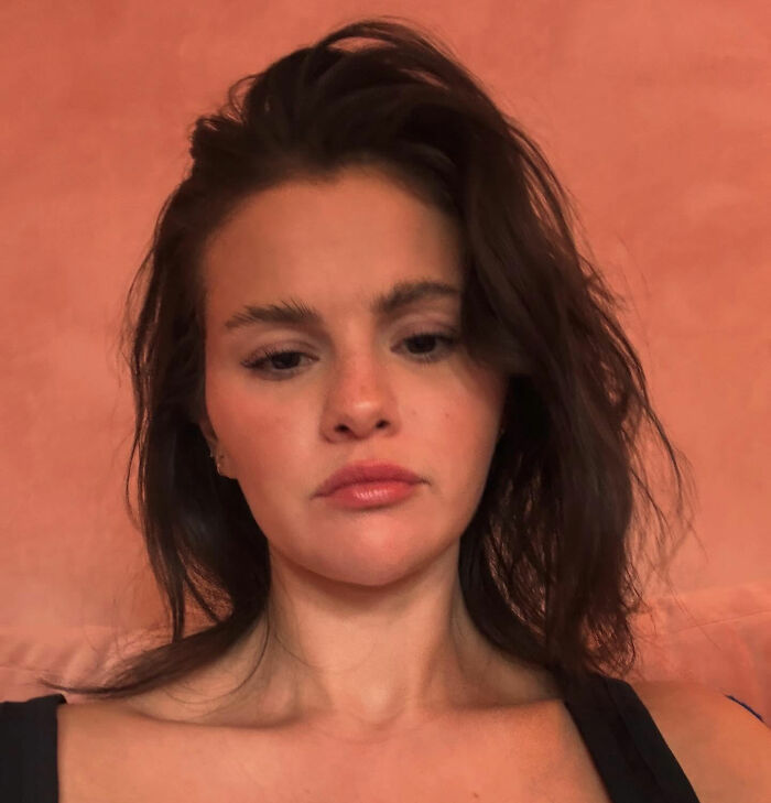 Selena Gomez with tousled hair and natural makeup, sharing her response about how she shaves her mustache.