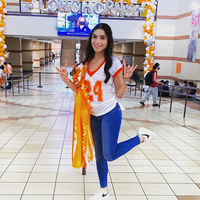 Young cheerleader posing in school hallway with orange ribbons and wearing number 24 jersey related to cheerleader phone clue case