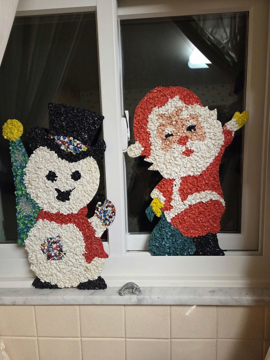 Nostalgic vintage Christmas decorations of a snowman and Santa made from colorful textured materials on a window.