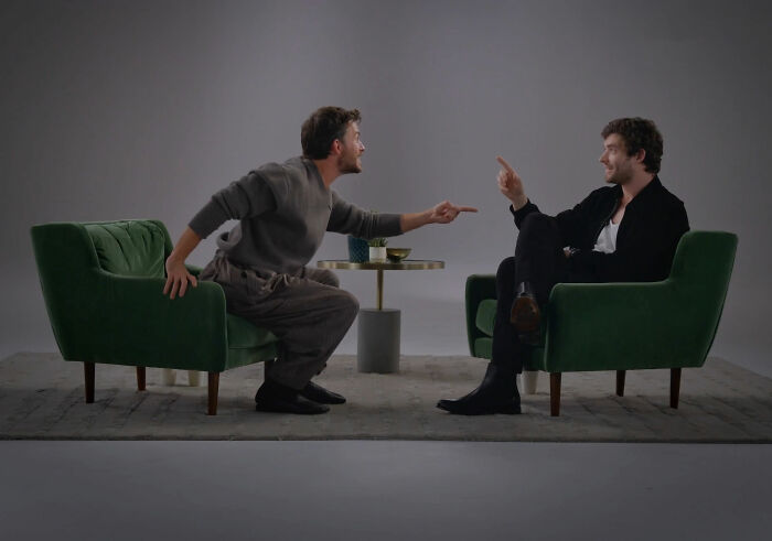 David Corenswet and Jonathan Bailey seated in green chairs, engaged in a lively discussion about masculinity perspectives.