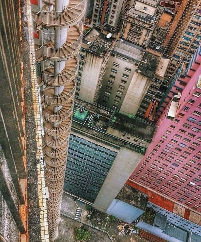 View looking down a tall building with a spiral fire escape causing fear for those with megalophobia.