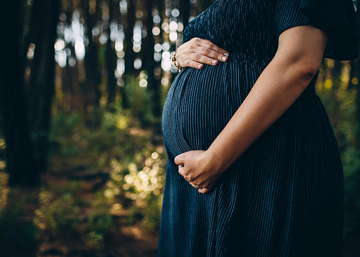 Pregnant woman in a dark dress holding belly, symbolizing wild stories shared about ex relationships and surprises.