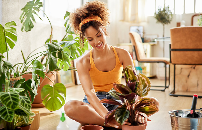 Young woman with curly hair caring for indoor plants, showcasing natural traits men find attractive in women.