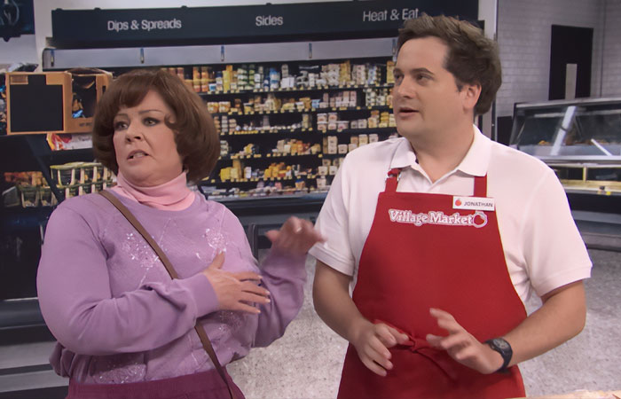 Melissa McCarthy in a grocery store scene, wearing a purple sweater, highlighting her jaw-dropping 95-pound weight loss.
