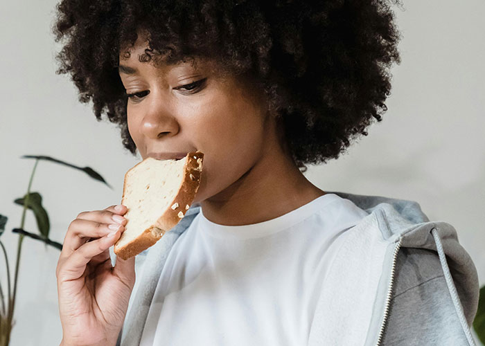 Young person eating bread indoors, illustrating everyday moments unrelated to luxury industry rip-offs discussed expert insights.