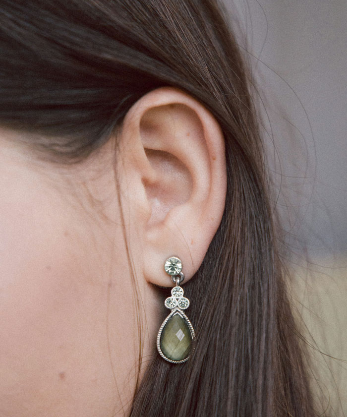 Close up of a woman’s ear wearing an elegant earring, illustrating embarrassing moments in front of doctors context.