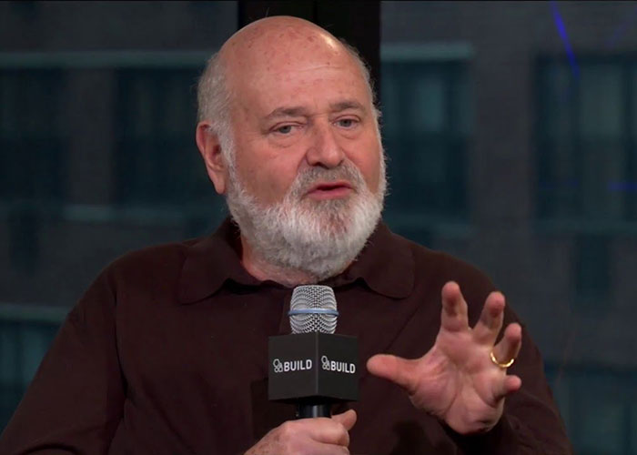 Rob Reiner speaking at a BUILD event, holding a microphone and gesturing while discussing political controversies involving Trump. Rob Reiner speaking at a BUILD event, holding a microphone and gesturing while discussing political controversies involving Trump.