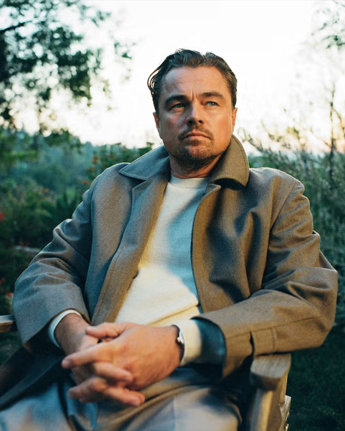 Leonardo DiCaprio sitting outdoors in a coat, looking thoughtful, related to Jennifer Lawrence mocking DiCaprio&rsquo;s dating history.