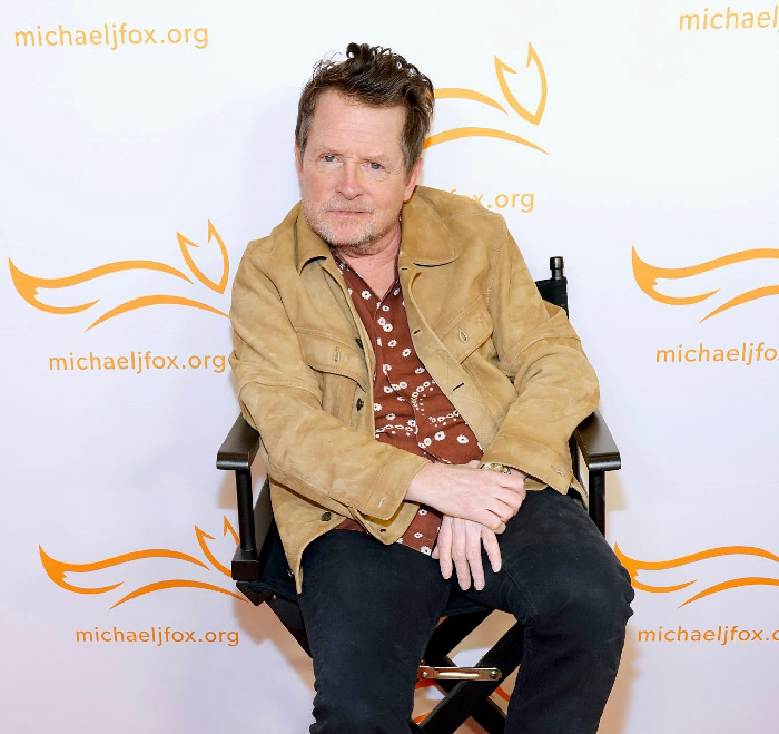 Michael J. Fox seated at a michaeljfox.org event, representing celebrities with rare conditions raising awareness and inspiring others.