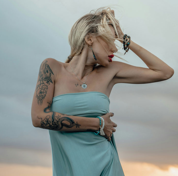 Woman with tattoos and blonde hair posing outdoors showing things women do to seem attractive men can't stand