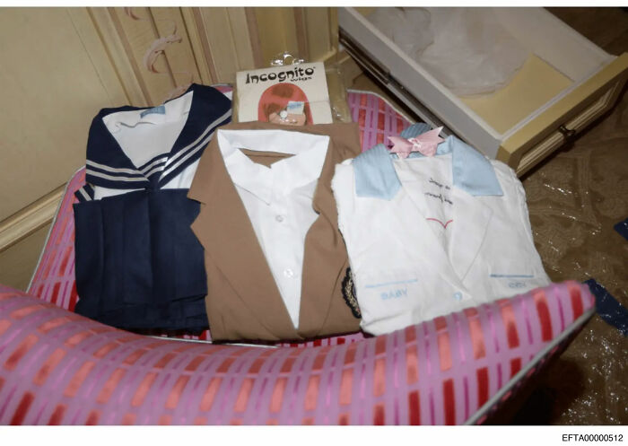 Role-play costumes laid out on a bed exposing troubling art from the Epstein file dump in a NYC townhouse setting.