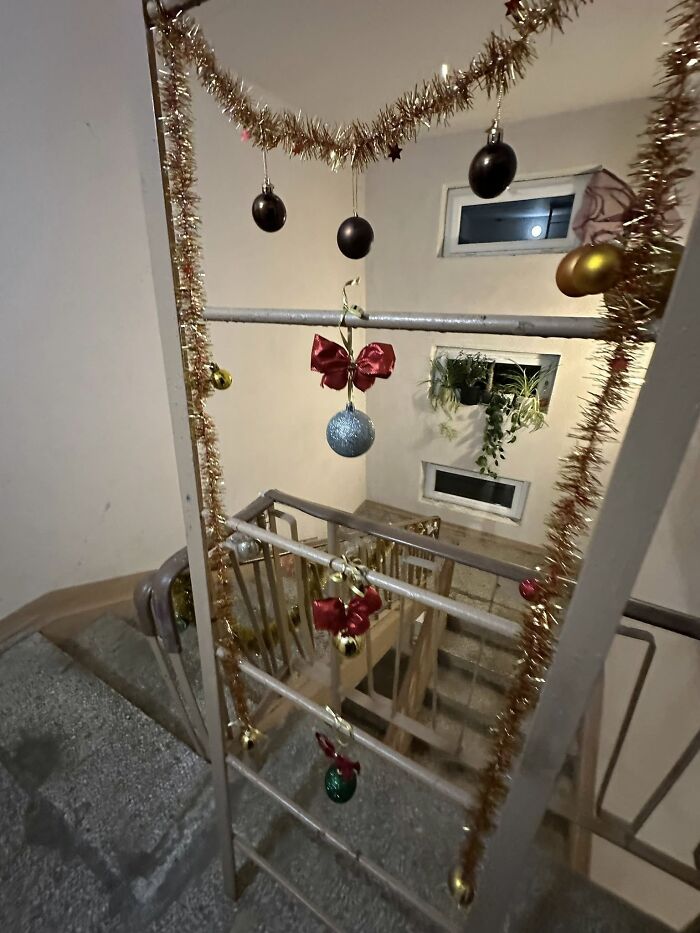 Christmas decorations with tinsel, bows, and baubles hanging in a Lithuanian apartment building stairwell.
