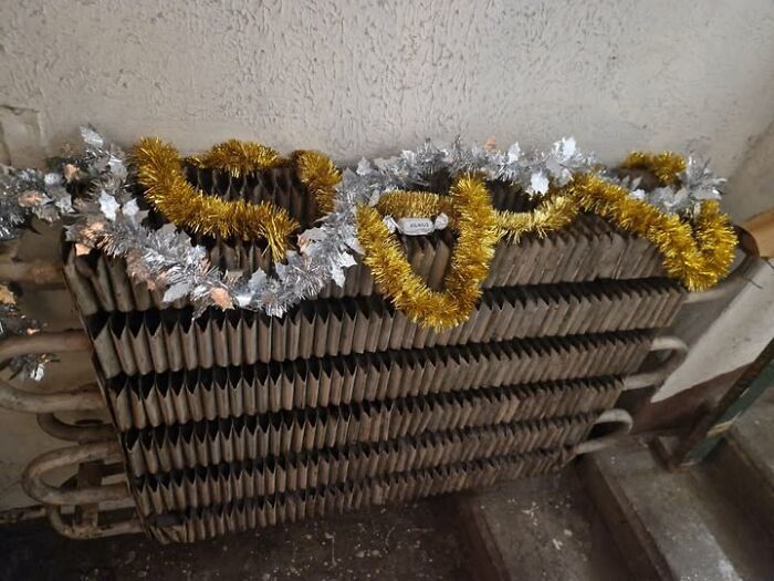 Old apartment radiator decorated with silver and gold tinsel as a quirky Lithuanian Christmas decoration.