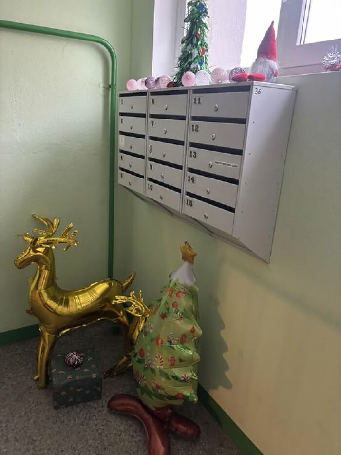 Christmas decorations with golden reindeer balloons and festive ornaments in a Lithuanian apartment building hallway.