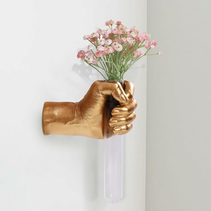 Gold hand wall vase holding pink flowers, a quirky gift for the friend with gloriously unhinged taste.
