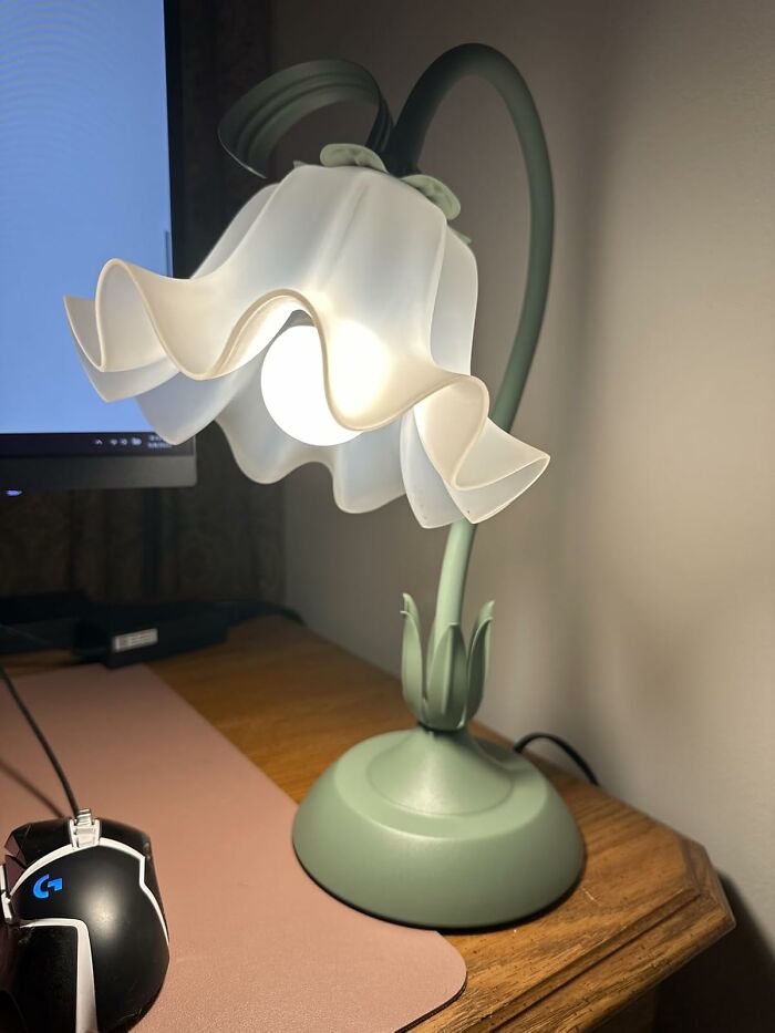 Green flower-shaped desk lamp glowing warmly near computer and gaming mouse as a quirky gift idea for unhinged taste friends.