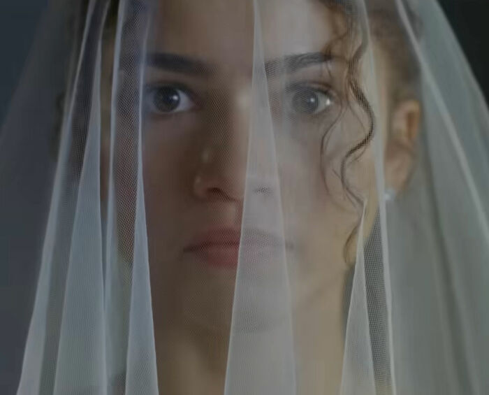 Zendaya wearing a bridal veil, looking through sheer fabric in a viral engagement ring ad related to Robert Pattinson. Zendaya wearing a bridal veil, looking through sheer fabric in a viral engagement ring ad related to Robert Pattinson.