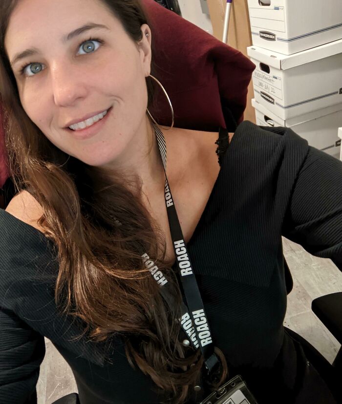 Woman with long brown hair smiling, wearing hoop earrings and a ROACH lanyard, showing confidence after a leap of faith.