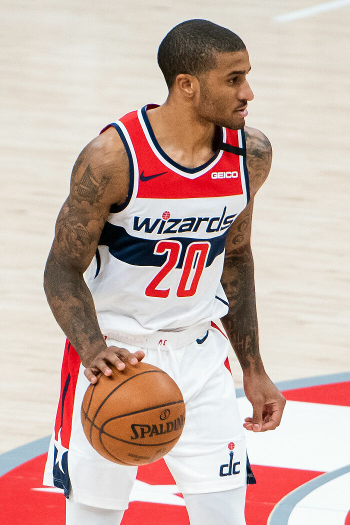 Gary Payton II dribbling basketball on court wearing Wizards uniform during a professional game.