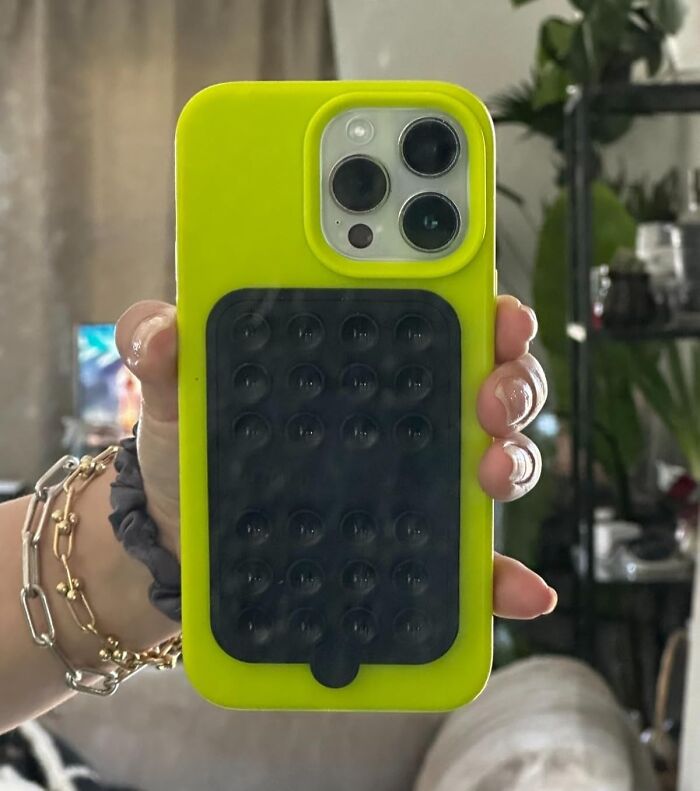 Bright yellow phone case with black pop-it fidget toy held by hand, one of the popular gifts teens are begging for this year.