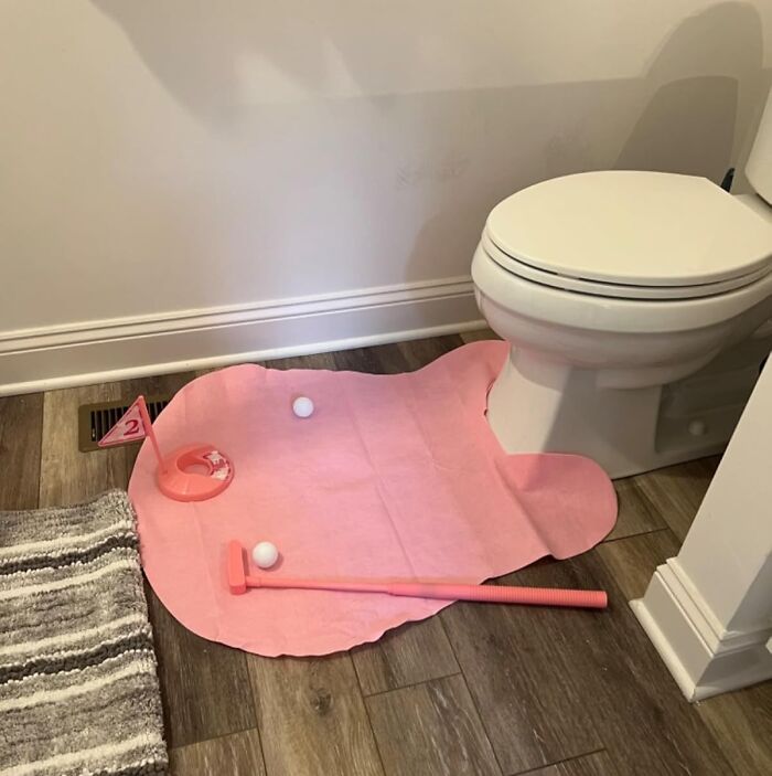Mini indoor golf set on a pink mat placed in front of a toilet, a quirky gift for the gloriously unhinged friend.