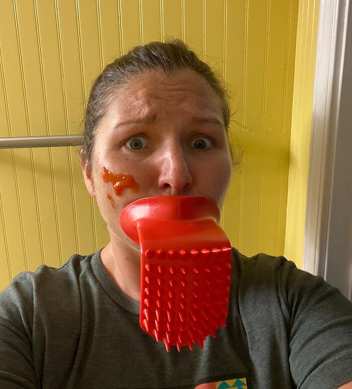 Person with a quirky red kitchen utensil in mouth and sauce on face, illustrating quirky gifts for gloriously unhinged friends.