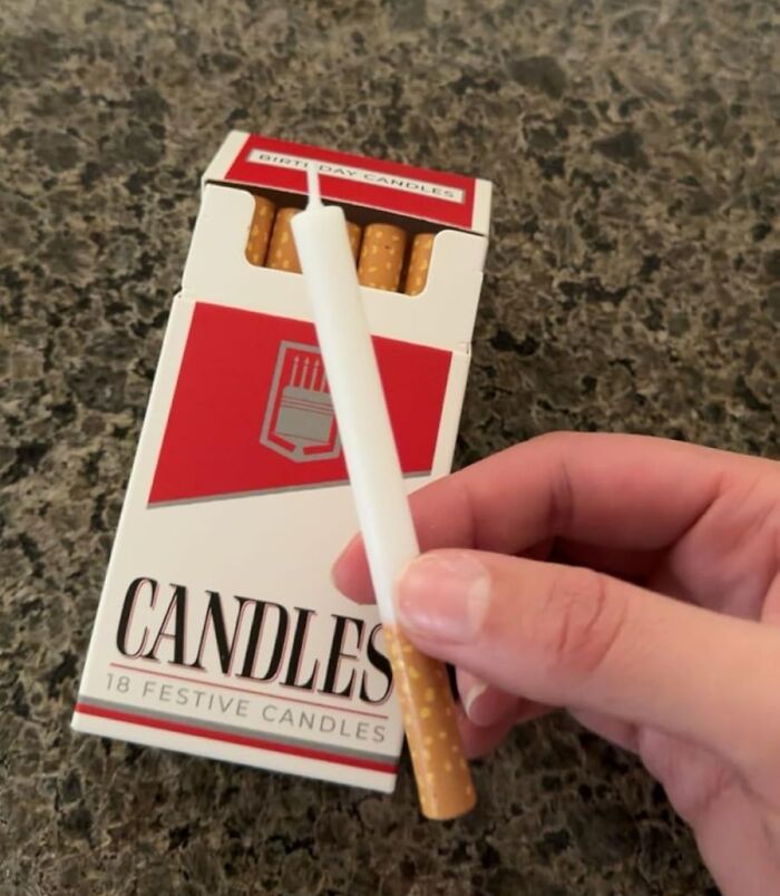 Hand holding a birthday candle designed to look like a cigarette from a pack of quirky gifts candles.
